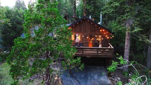 A cabin with a deck, surrounded by trees.