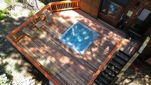 Una terraza de madera con un jacuzzi, sillas y una valla de madera.