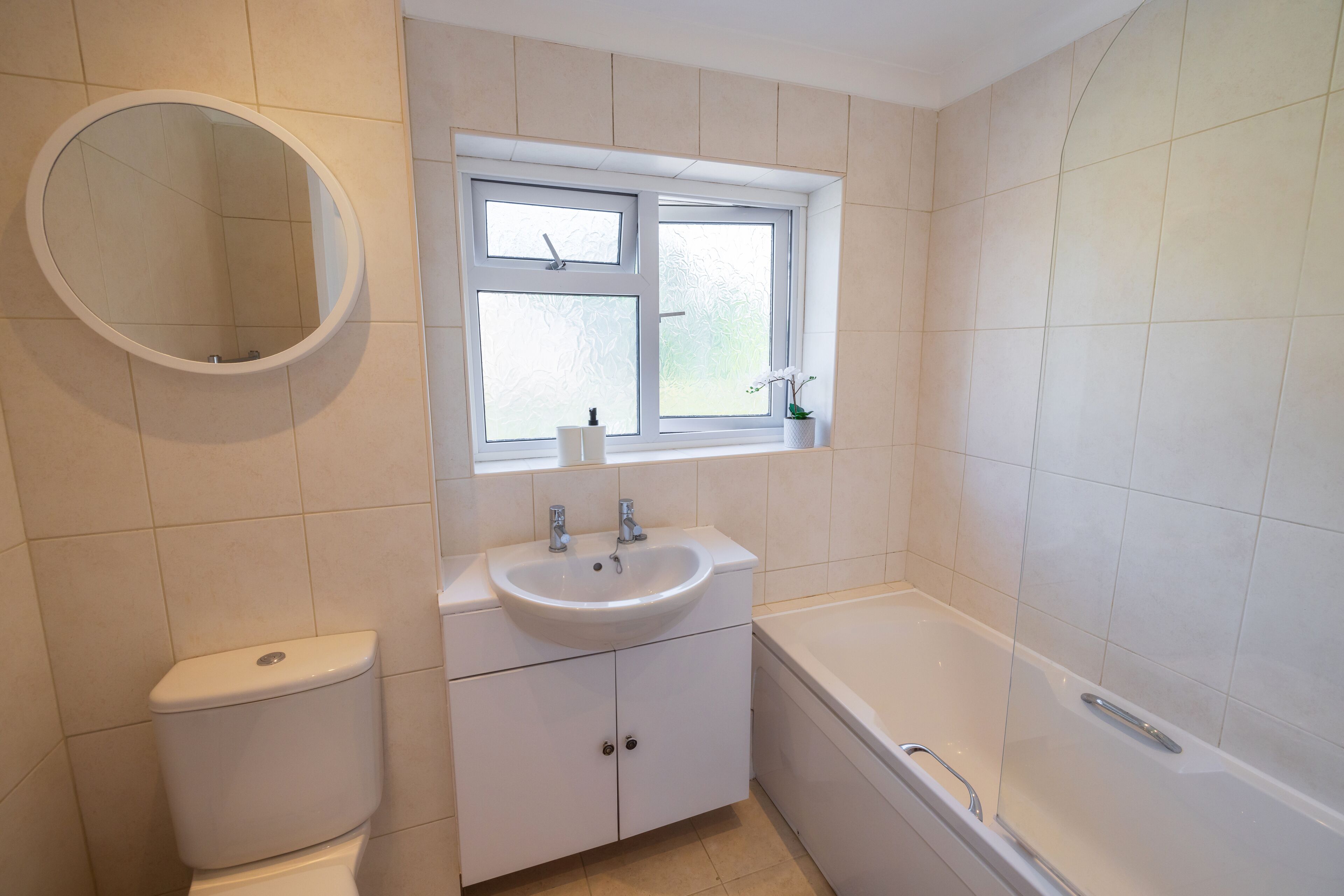 Et badeværelse med toilet, vask, vindue og badekar.