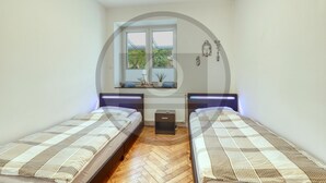 Ein Schlafzimmer mit zwei Einzelbetten, einem Fenster mit Blick ins Grüne und einer Heizung.