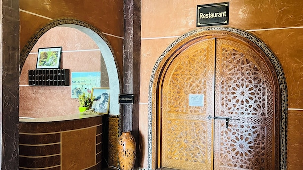 Un espace d’accueil comprenant un comptoir de réception, un panneau indiquant « Réception » et une porte portant l’inscription « Restaurant ».