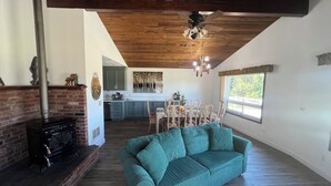 A living room with a green sofa, a fireplace, and a dining area in the background. - Quaint, Rustic Charm Lake house with WiFi in Cascade. (Cascade)