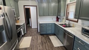 A modern kitchen with grey cabinets, stainless steel appliances, and a wooden floor. - Quaint, Rustic Charm Lake house with WiFi in Cascade. (Cascade)