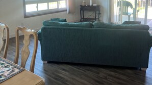 A room with a wooden ceiling, a large bed with a green cover, a TV mounted on the wall, and a dining area with a table and chairs. - Quaint, Rustic Charm Lake house with WiFi in Cascade. (Cascade)