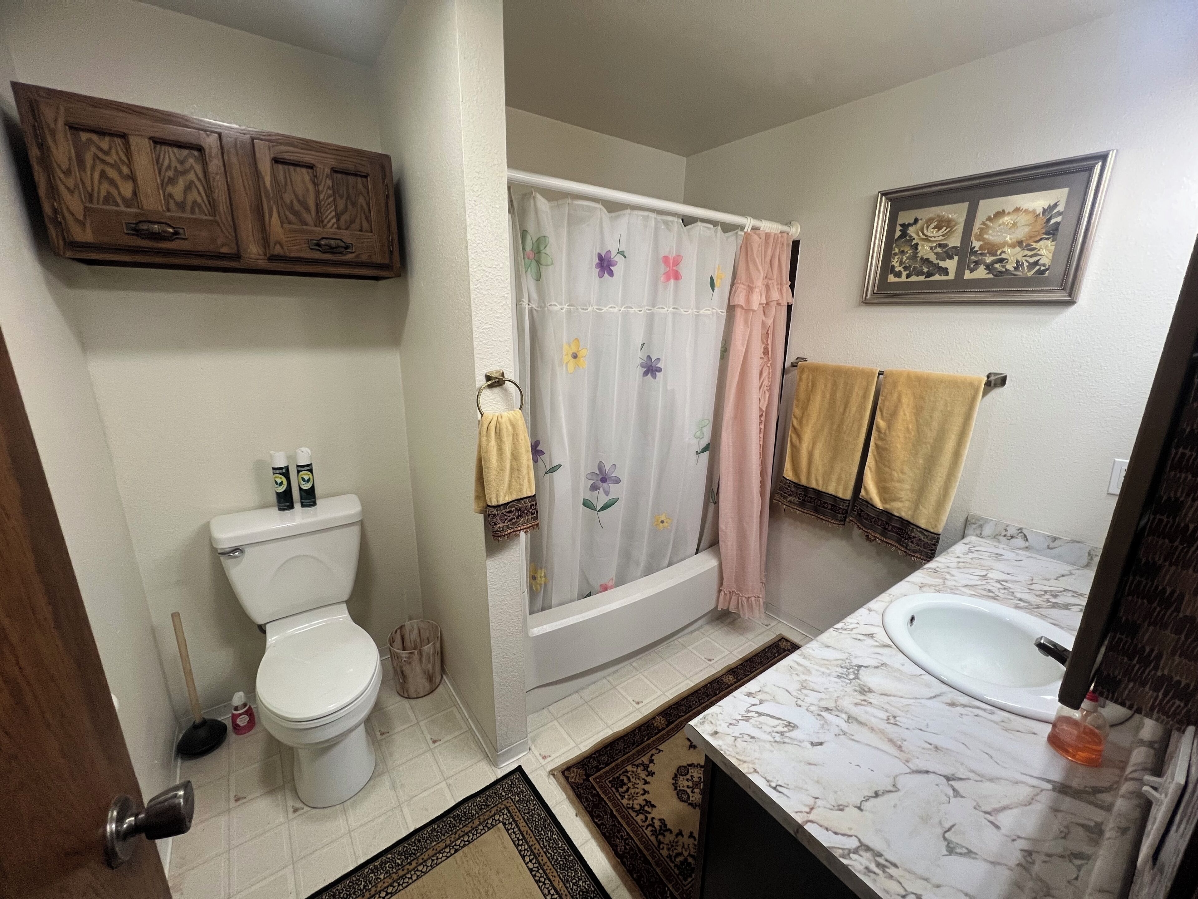 Une salle de bain équipée de toilettes, d’un lavabo, d’un rideau de douche et de deux serviettes.