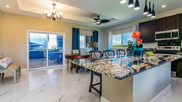 A modern kitchen with a marble island, dark cabinets, and a ceiling fan. - Hilo Hibiscus Vacation Home 3 bedrooms  (Hilo)