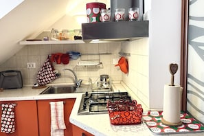 A kitchen with a gas stove, a sink, and various kitchen utensils.