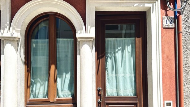 Un bâtiment avec une porte marron et une fenêtre avec un rideau.