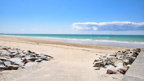 Una playa con costa rocosa y vista despejada del océano.