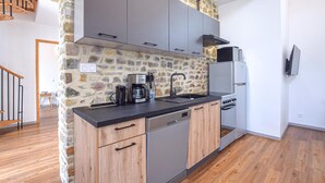 Una cocina moderna con armarios grises, una pared de acento de piedra y suelo de madera.