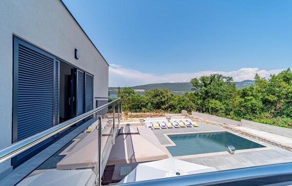Relax by the pool surrounded by lush greenery and a distant landscape view.