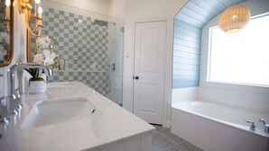 A modern bathroom with a large bathtub, a separate shower area, and a vanity with a sink and mirror. - Huge 4BR w/ Pool + Grill | Near Lakes and Harbor! (Royse City)