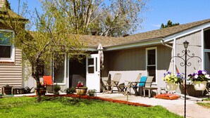 A residential house with a covered porch, outdoor seating, and potted plants.