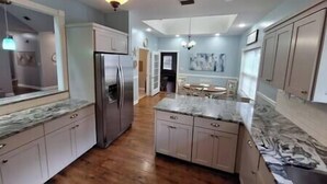 A spacious kitchen with a central island, wooden flooring, and light blue walls. - Homerun Hideaway! Beach/OWA/Sports/Shopping (Foley)