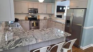 A kitchen with a marble countertop, stainless steel appliances, and white cabinetry. - Homerun Hideaway! Beach/OWA/Sports/Shopping (Foley)