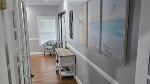 A hallway with wooden flooring, a bench, and a wall-mounted cabinet. - Homerun Hideaway! Beach/OWA/Sports/Shopping (Foley)