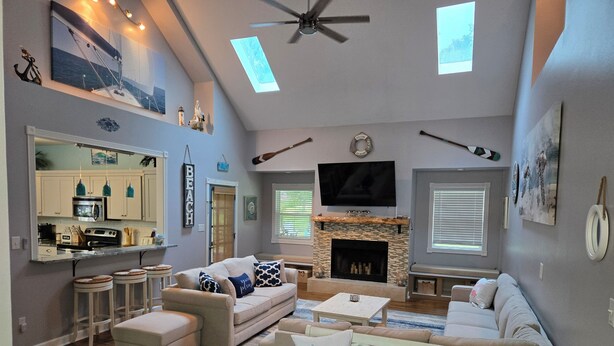 A spacious living room with a fireplace, a television, and a ceiling fan. - Homerun Hideaway! Beach/OWA/Sports/Shopping (Foley)