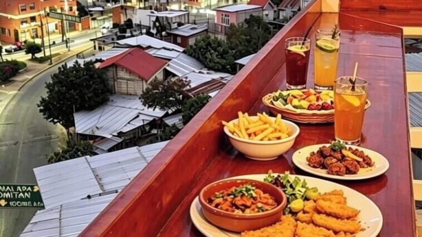 A table with food and drinks, overlooking a street with buildings. - HOTEL LINDA VISTA (Motozintla)