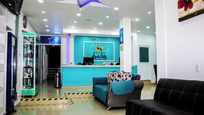 A hotel reception area with a blue counter, a black sofa, and a glass display case. - HOTEL LINDA VISTA (Motozintla)