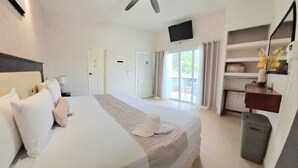 A hotel room with a bed, a desk, a chair, a television, and a sliding glass door leading to an outdoor area. - HOTEL LINDA VISTA (Motozintla)
