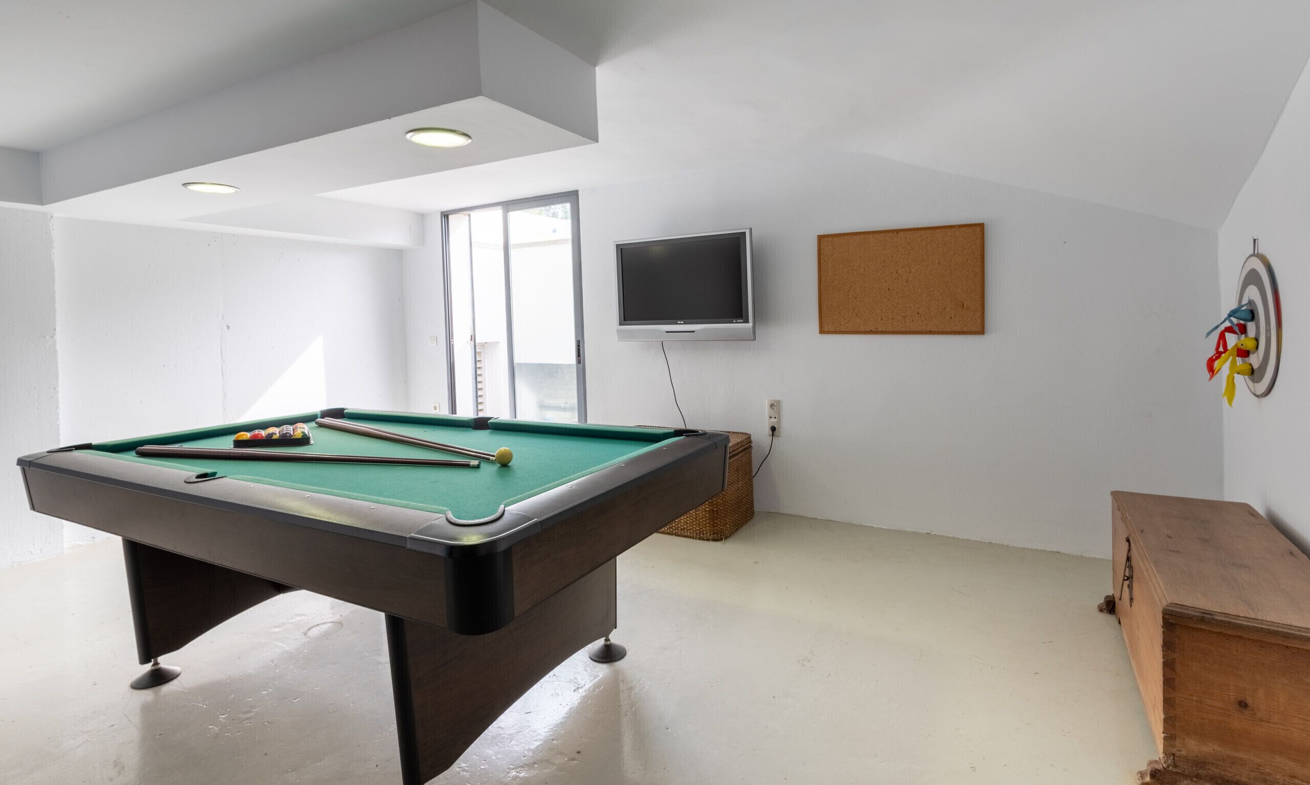 Une table de billard dans une pièce équipée d’un téléviseur et d’un panneau d’affichage mural.