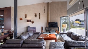A modern living room with a brick wall, leather sofas, a flat-screen TV, and a large window offering a view of the outdoors. - Ref. 494261 (Motril)