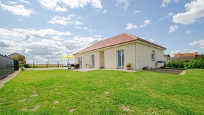 A single-story house with a red-tiled roof, a covered patio, and a well-maintained lawn. - La Maiziéroise - SAVIERES (SAVIERES)
