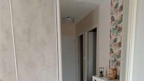 A hallway with a sliding door, a cabinet with decorative items, and a patterned wall. - La Maiziéroise - SAVIERES (SAVIERES)