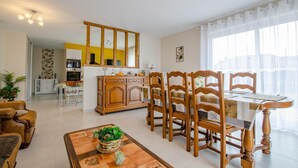 A dining area with wooden chairs and a table, a kitchen with a microwave and oven, and a living area with a sofa and a coffee table. - La Maiziéroise - SAVIERES (SAVIERES)
