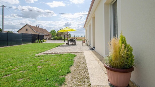 A residential backyard with a lawn, a gravel path, a patio area with outdoor furniture, and a yellow umbrella. - La Maiziéroise - SAVIERES (SAVIERES)