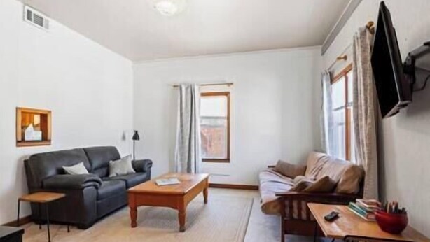 A living room with two sofas, a coffee table, and a TV mounted on the wall. - Depot Suite (Elkader)