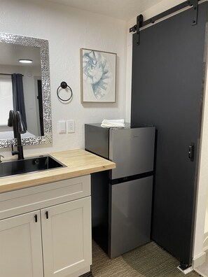 A compact kitchen with a sink, a refrigerator, and a sliding door.