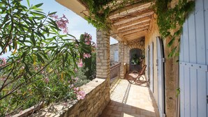 A stone-built outdoor patio with a wooden pergola, a rustic door, and a chair. - Gorgeous home in Clansayes Clansayes (clansayes Clansayes)