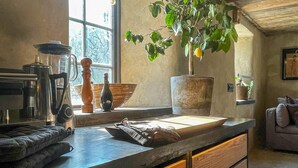 Een keuken met een groot raam, een plant en diverse keukenspullen.