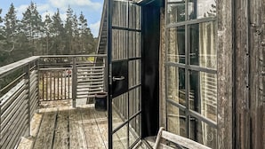 Een houten terras met een glazen deur naar een kamer.