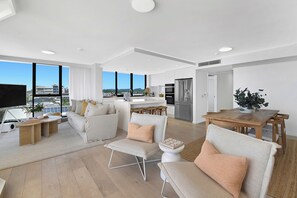 A modern living room with a sofa, chairs, a coffee table, and a dining table.