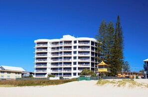 A multi-story hotel with balconies, a lifeguard tower, and a beach in the background. -  Oceanfront Escape - SeaHaven on Albatross Avenue (Mermaid Beach)