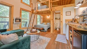 A cozy cabin interior with a loft bedroom, a dining area, and a kitchen.