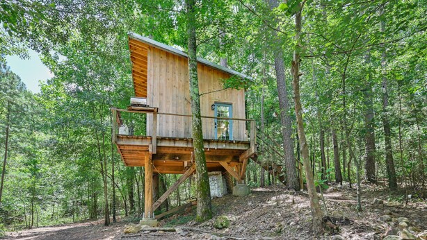 A wooden treehouse elevated on stilts in a forest.