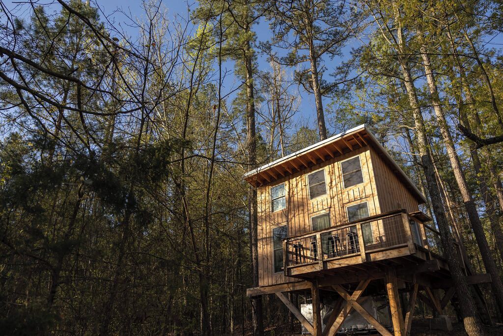 A wooden cabin with a balcony, surrounded by a forest.