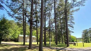 A campground with tall pine trees, a small cabin, and a picnic area. - Cedar Loft Suite at Sacred Pines Lodge (Scott County)