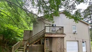 A two-story wooden house with a balcony, a garage, and a wooden deck. - Cedar Loft Suite at Sacred Pines Lodge (Scott County)