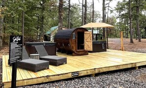 A wooden deck with outdoor seating, a covered area, and a spa sign. - The Lodge at Sacred Pines (Scott County)