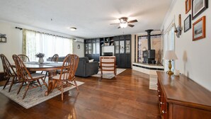 A spacious living room with a dining area, a fireplace, and a kitchen in the background. - The Lodge at Sacred Pines (Scott County)