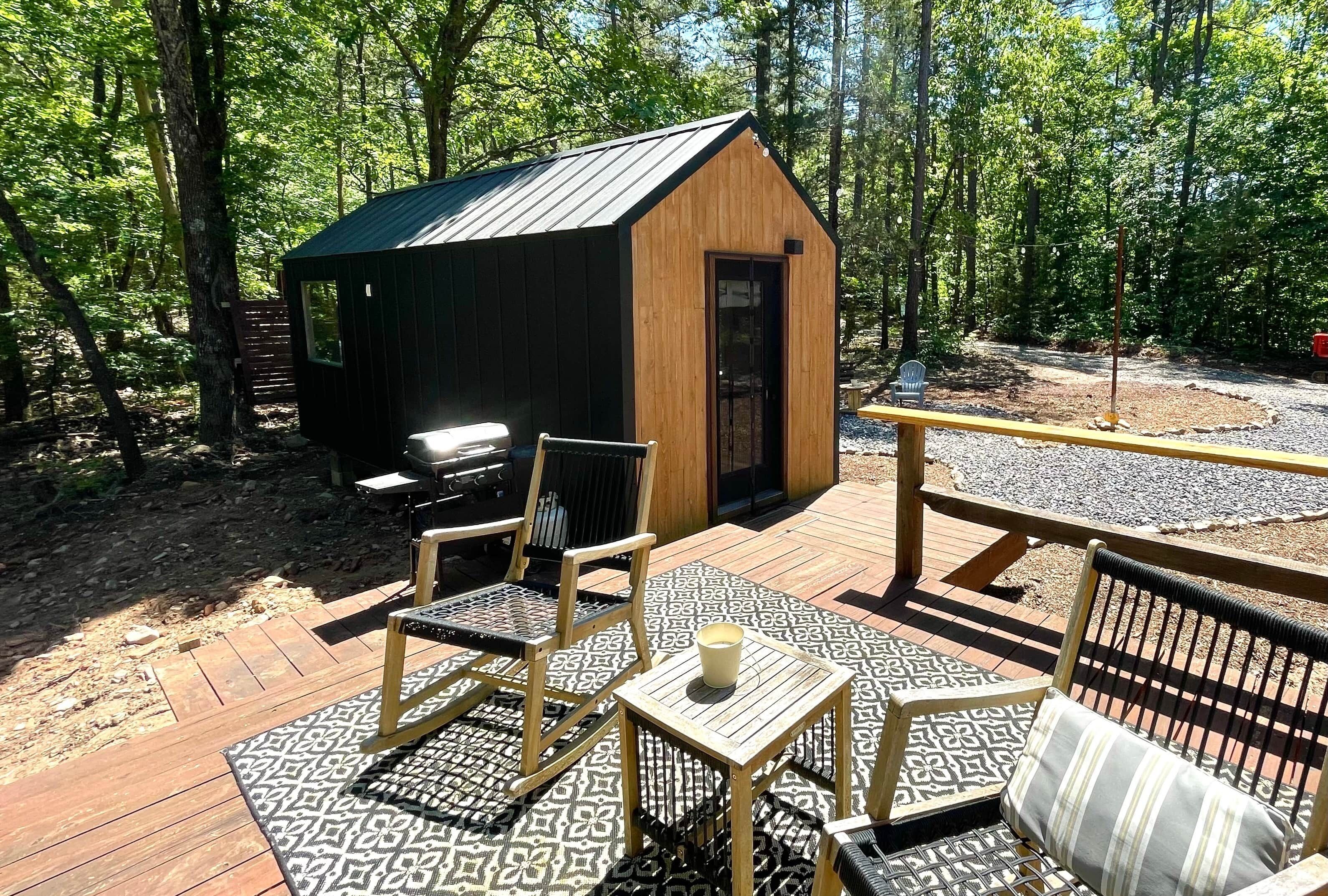Une terrasse en bois avec des meubles d’extérieur, un petit abri de jardin et un espace barbecue.