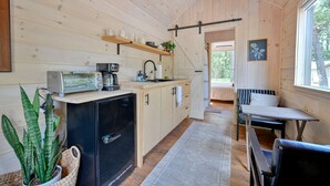 A wooden interior with a kitchen area, a dining table, and a bench. - Nordic Tiny House (Scott County)