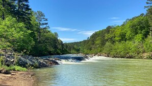 A river flowing through a forested area with dense trees on both sides. - Nordic Tiny House (Scott County)