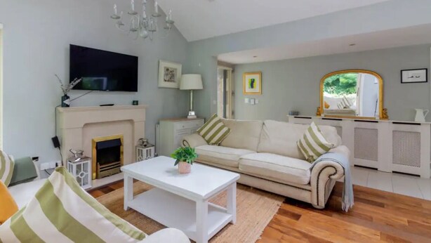A living room with a fireplace, a sofa, a TV, and a mirror. - Two bedroom Apartment  (Malahide)