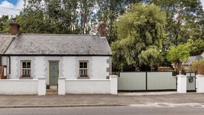 A white single-story house with a grey roof, a green door, and a small window on the front. - Two bedroom Apartment  (Malahide)