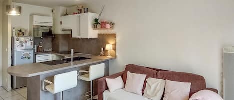 Een compacte leefruimte met een kitchenette, een bank en een salontafel.